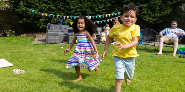 zwei Kinder rennen durch einen dekorierten Garten