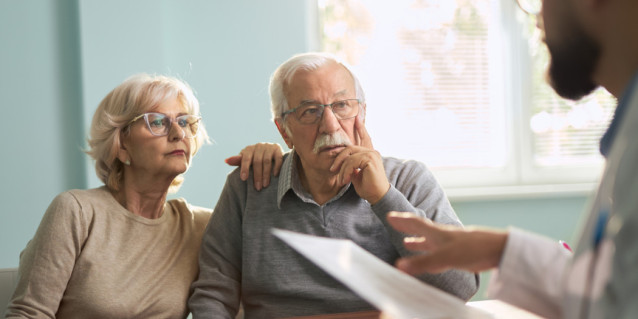 Älteres Paar auf Sofa Gespräch mit Mann mit Vertrag