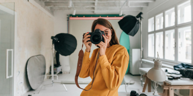 Frau in Studio macht Foto mit Kamera