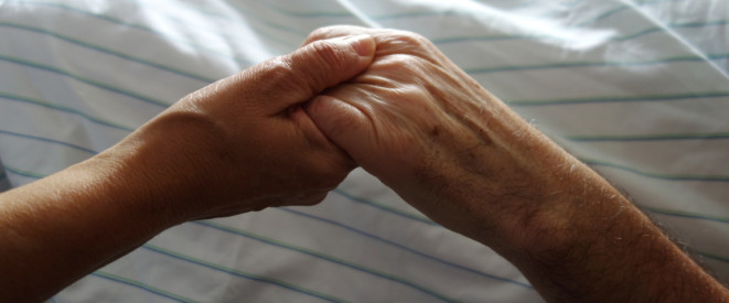 Junge Hand hält alte hand am Krankenhausbett