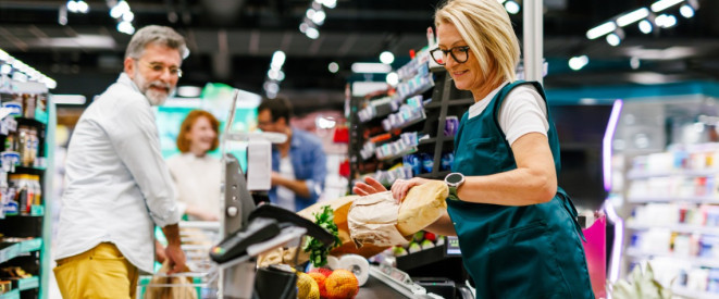 Mann kauft bei Kassiererin an einer Supermarktkasse ein