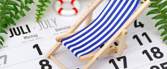 Nahaufnahme kleiner Spielzeug-Liegestuhl und -Schwimmring stehen auf Kalender