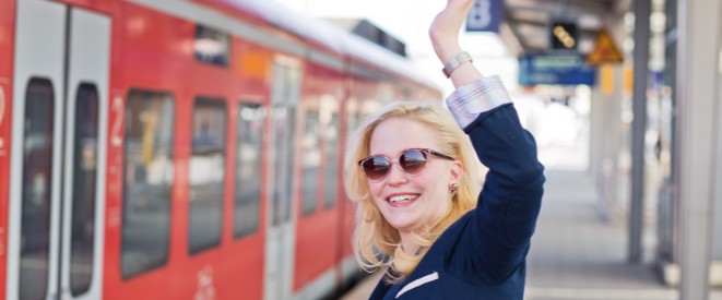 winkende Frau am Bahngleis vor der Bahn