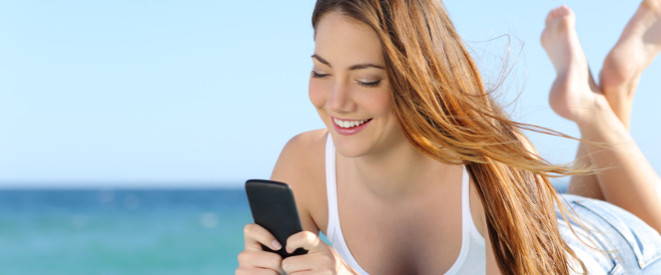 junge Frau mit Handy am Strand