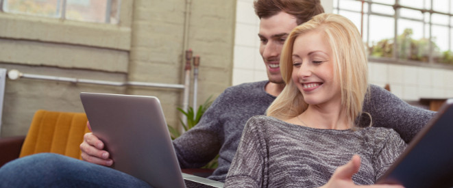 Paar sitzt auf der Couch vor dem Computer