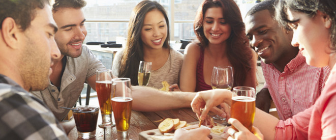internationale junge Menschen am sitzen am Tisch und trinken Bier und Wein