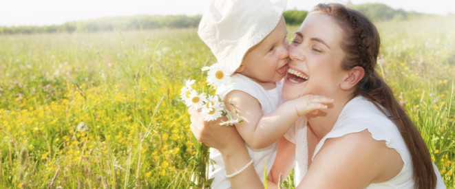 Mütterrente: junge Mutter mit Kind auf dem Arm auf einer Wiese