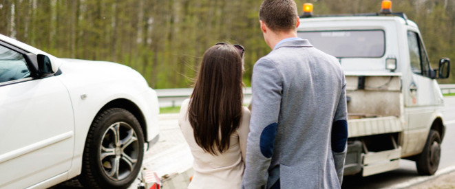 junges Paar sieht zu, wie ihr Auto abgeschleppt wird