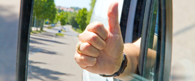 Autofahrer hält Faust mit Daumen hoch aus dem Autofenster