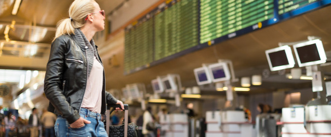 Flug verpasst: Frau blickt auf die Anzeigentafel am Flughafen