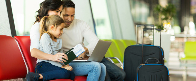 Familie mit Reisegepäck am Flughafen schauen auf einen Laptop
