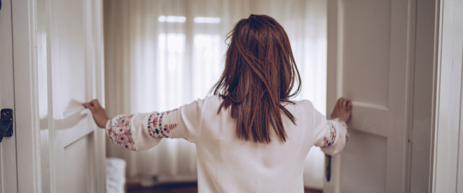 Zwei junge Frauen in Jeans und Sweatshirts sitzen auf dem Boden vor einem Laptop, um sie herum viele Umzugskartons