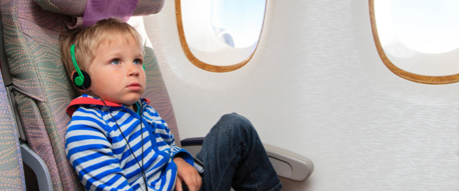 Kleinkind mit Kopfhörern im Flugzeug