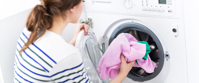 Waschen im Mietshaus: Junge Frau füllt Waschmaschine