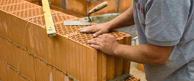 Nahaufnahme: Handwerker mauert eine Hauswand