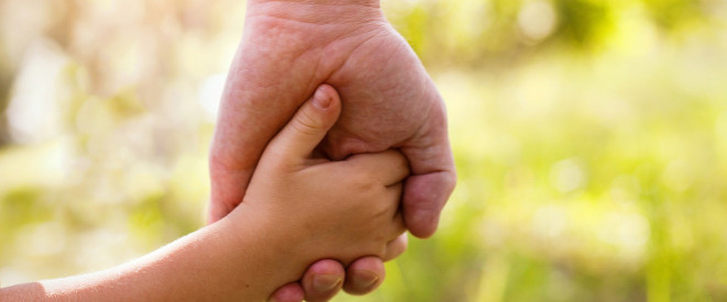 Adoption: Erwachsenenhand hält Kinderhand