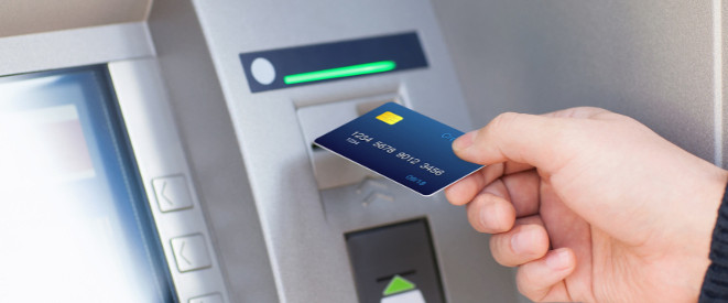 Hand führt Bankkarte in Geldautomaten ein
