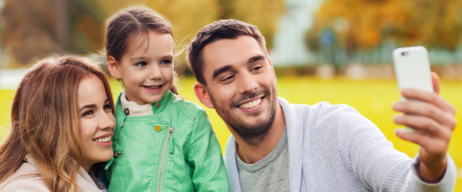 Kinderfotos auf Facebook: Lächelnde Eltern mit kleiner Tochter machen ein Selfie mit dem SmartphoneKinderfotos auf Facebook: Lächelnder Vater mit kleiner Tochter