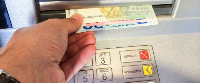 Cash Trapping: Ein Hand zieht Geldscheine aus einem Geldautomaten.