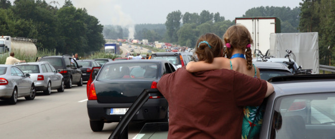 Frau hält Kind im Arm und schaut auf die Fahrbahn