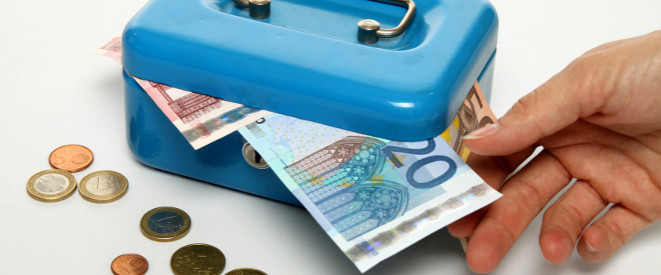 Diebstahl am Arbeitsplatz: Eine Hand, die einen 20-Euro-Schein aus einer gefüllten Geldkassette zieht.