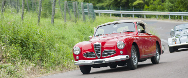 H-Kennzeichen: Ein roter Oldtimer in einer Kurve.