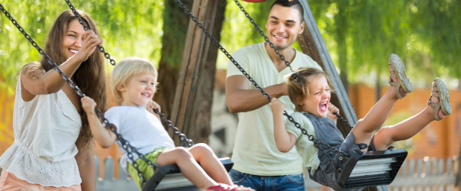 Patchworkfamilie und Unterhalt: Die Rechtslage. Zwei kleine Kinder werden von ihren Eltern auf der Schaukel angeschubst.