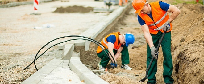 Straßenausbaubeiträge: Die Rechtslage für Anwohner. Zwei arbeitende Straßenbauarbeiter mit orangenen Sicherheitswesten.