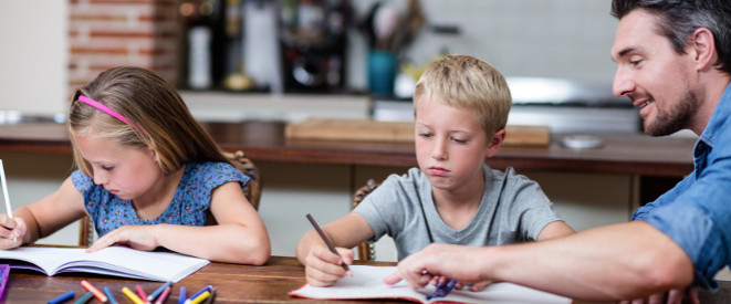 Hausaufgaben: Wie sind sie rechtlich geregelt? Ein Mann sitzt mit einem Jungen und einem Mädchen an einem Tisch und hilft bei den Hausaufgaben.