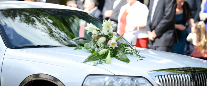 Konvoi fahren: Die Regeln für Hochzeitskonvoi und Co. Ein silbernes Auto auf dessen Motorhaube eine Hochzeitsstrauß befestigt ist.