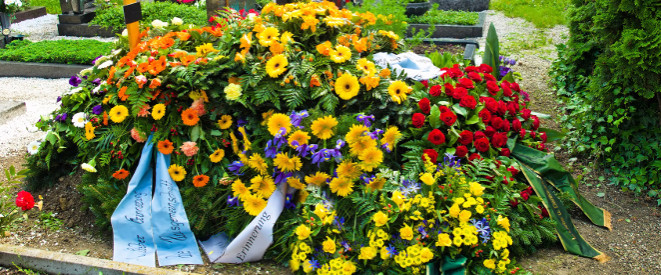 Nachlassverbindlichkeiten: Das müssen Erben wissen Ein Grab auf dem viele Blumengestecke liegen.