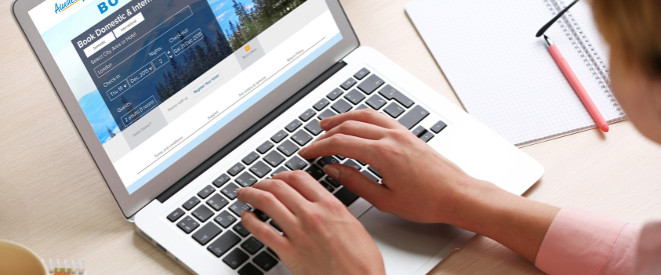 Urlaub online buchen: Tipps für mehr Sicherheit. Eine Frau sitzt an einem Laptop und surft auf der Seite einer Reiseseite.