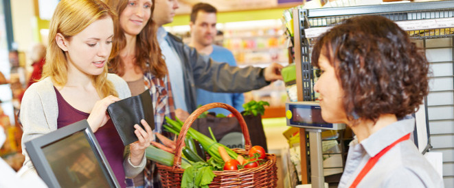 500-Euro-Schein wechseln: Dürfen Händler ihn ablehnen? Eine junge Frau steht an einer Supermarktkasse und schaut in ihr Portemonnaie.