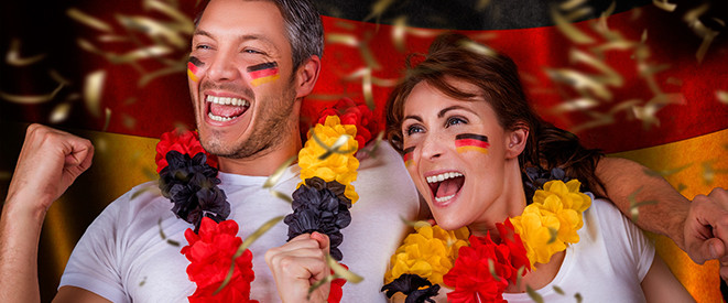 EURO 2016 Top10-Tipps. Ein Mann und eine Frau sind mit Accessoires in den Farben Schwarz, Rot und Gold geschmückt und jubeln.