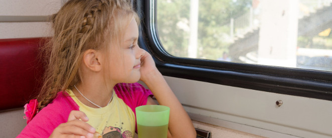 Alleinreisende Kinder: Fürsorgepflicht und andere Regeln. Ein kleines Mädchen sitzt im Zug und guckt aus dem Fenster.