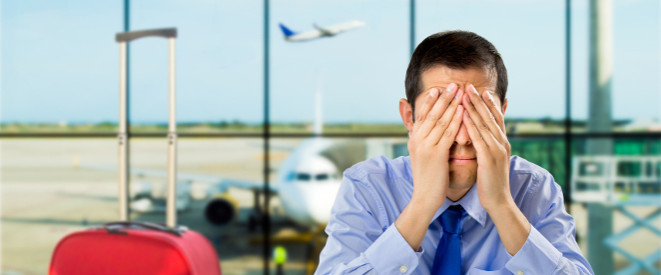 Fluggastrechte durchsetzen: Neue Leitlinien auf EU-Ebene. Ein Mann sitzt im Flughafen-Terminal und hält sich beide Hände vors Gesicht.