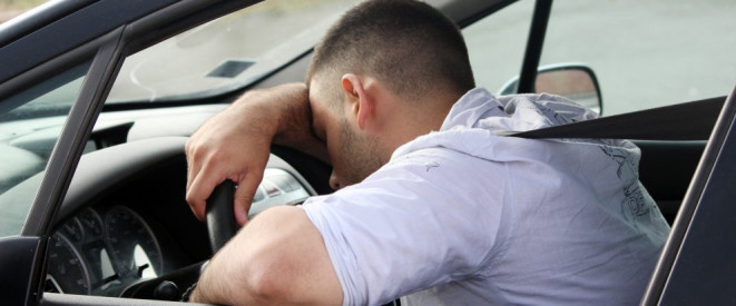 Trunkenheitsfahrt rechtfertigt fristlose Kündigung. Ein Mann lehnt auf dem Steuer eines Autos.