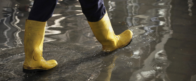 Gelbe Gummistiefel gehen durch Pfütze