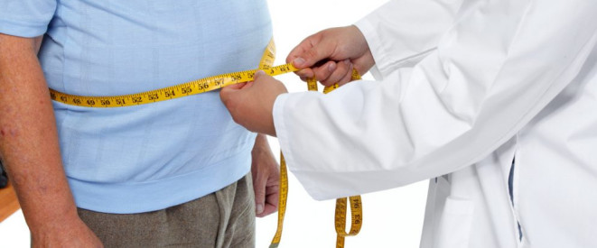 Krankheitsbedingte Kündigung wegen Übergewichts: Rechtens? Ein Arzt legt ein Maßband um den Bauch eines Mannes.