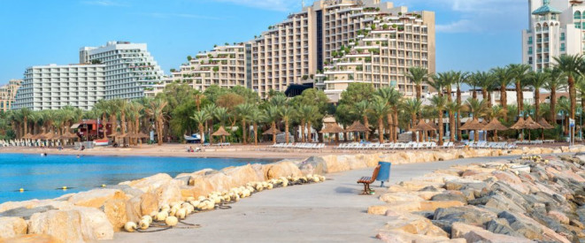 Strandhotel: Baustelle nicht immer ein Reisemangel. Eine Promenade, an deren Seiten große Steine aufgeschichtet sind, im Hintergrund sieht man mehrere Hotelkomplexe.