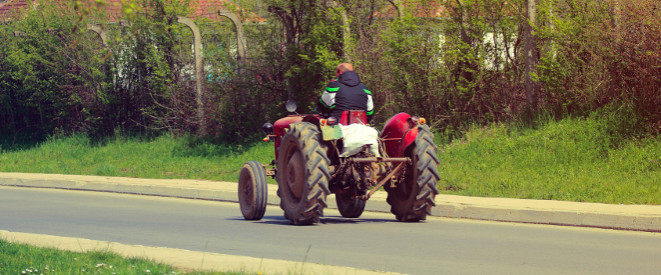 Ein roter Traktor fährt auf einer Landstraße.