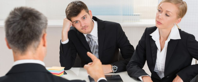 Arbeitgeber zahlt nicht: Das können Sie tun. Ein Mann und eine Frau in Business-Kleidung sitzen einem anderen Mann an einem Schreibtisch skeptisch gegenüber.