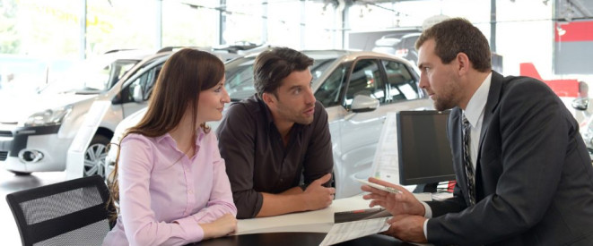 Kfz-Kaufvertrag: Rücktritt bei fehlender Ausstattung möglich. Ein Paar lässt sich im Autohaus von einem Mann im Anzug beraten.