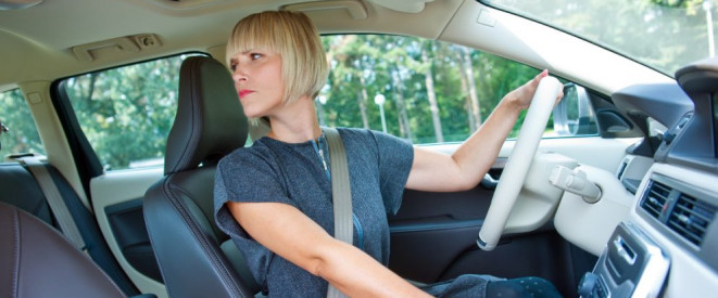 Rückwärtsfahren: Das erlaubt die StVO. Eine junge Frau sitzt im Auto und schaut nach hinten.