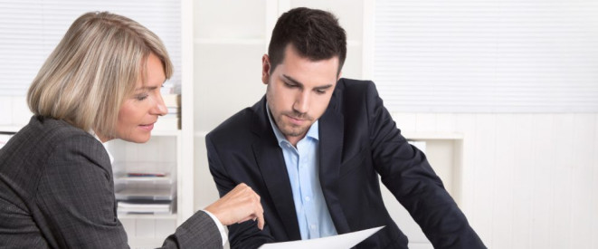 Personalgespräch: Rechte und Pflichten als Arbeitnehmer. Eine Frau zeigt einem jungen Mann in einem Büro ein Dokument.