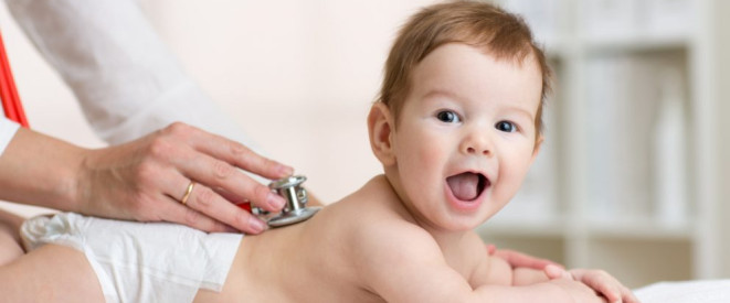 U-Untersuchungen beim Kinderarzt: Die neuen Regeln. Ein kleines Kind mit einer Windel liegt auf dem Bauch. Eine Ärztin legt ein Stethoskop auf seinen Rücken.