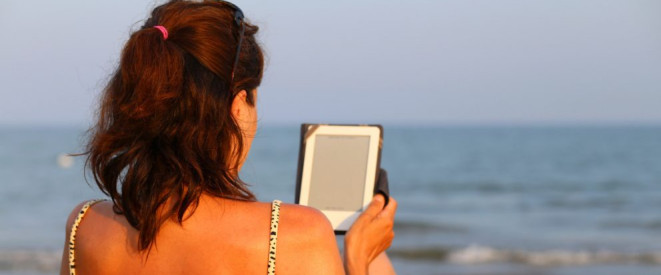 Buchpreisbindung bei eBooks: Bedeutung für Verbraucher. Eine Frau sitzt am Meer und hält einen eBook-Reader in der Hand.