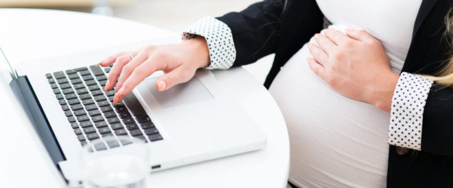 Mutterschutzgesetz: Neue Regelungen ab 2017. Ein schwangere Frau sitzt an einem Notebook und hält sich mit einer Hand den Babybauch.
