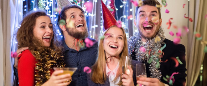 Nachtruhe an Silvester: Das sind die Regeln. Vier junge Männer und Frauen sind feierlich gekleidet. Konfetti regnet auf sie herab.