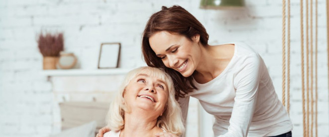 Pflegereform 2017: Wichtige Änderungen und Tipps. Eine jüngere Frau und eine ältere Frau, die sitzt, lachen sich an.